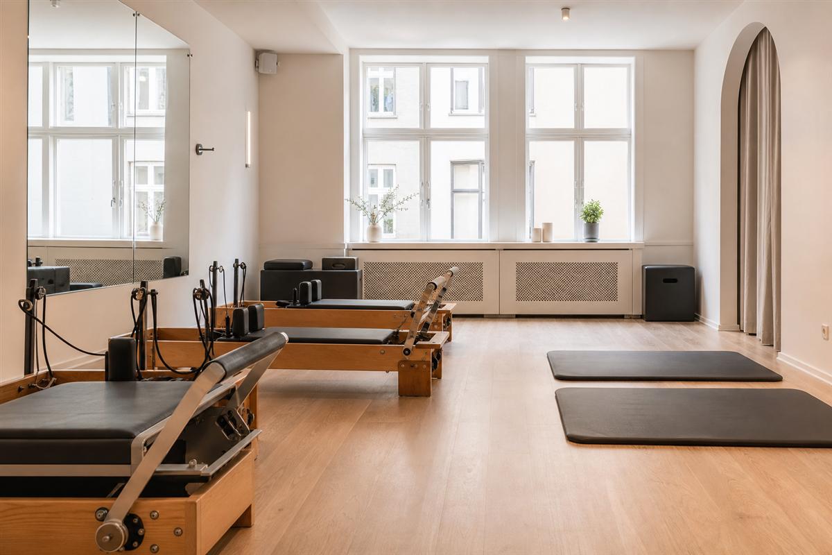 Pilates reformers and mats in a bright studio aisle